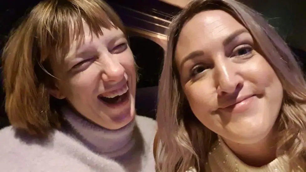 Two women are smiling towards the camera.
