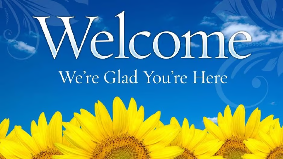 Title: Welcome. We’re glad you’re here. On a blue sky background with bright yellow sunflowers at the bottom.