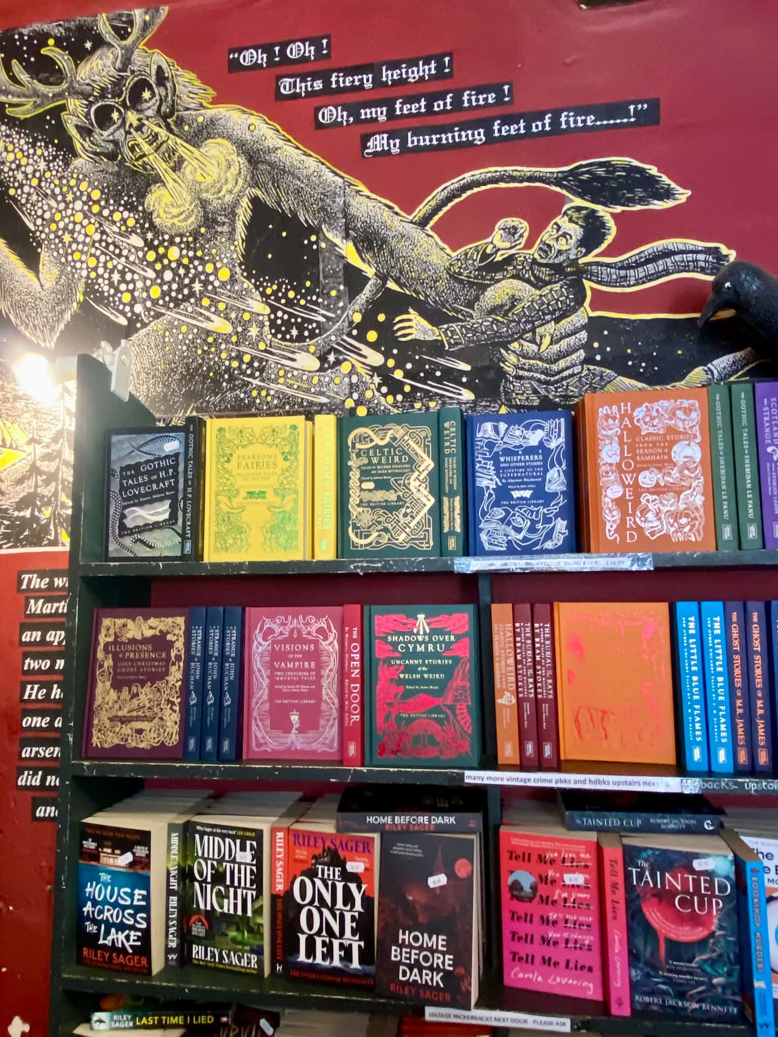 Brightly colored book displays sitting on shelves in front of a red wall decorated with a stylized yellow creature artwork and speech bubbles