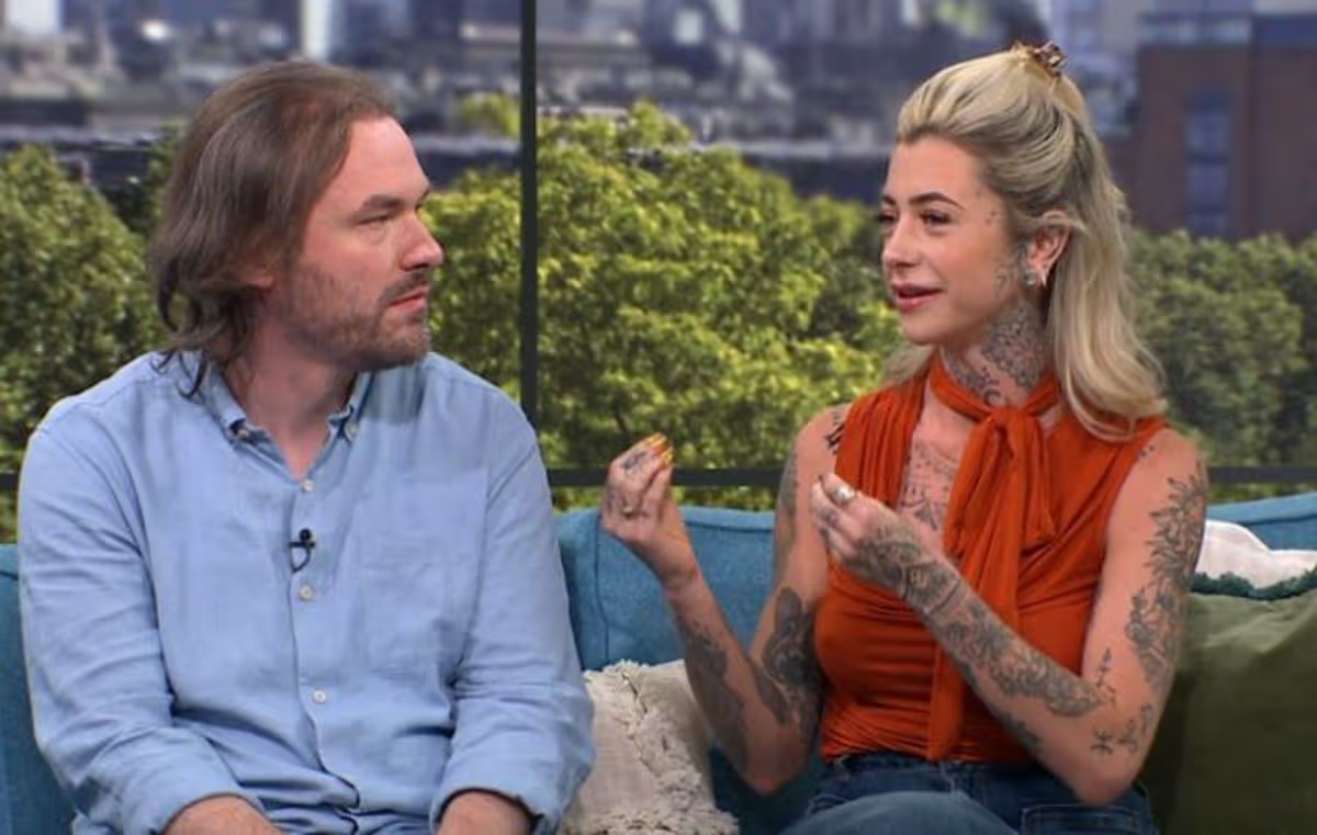 A screenshot of James and Saurora on the This Morning Sofa. Saurora is a white woman covered in tattoos. James has long brown hair and is looking at Saurora.