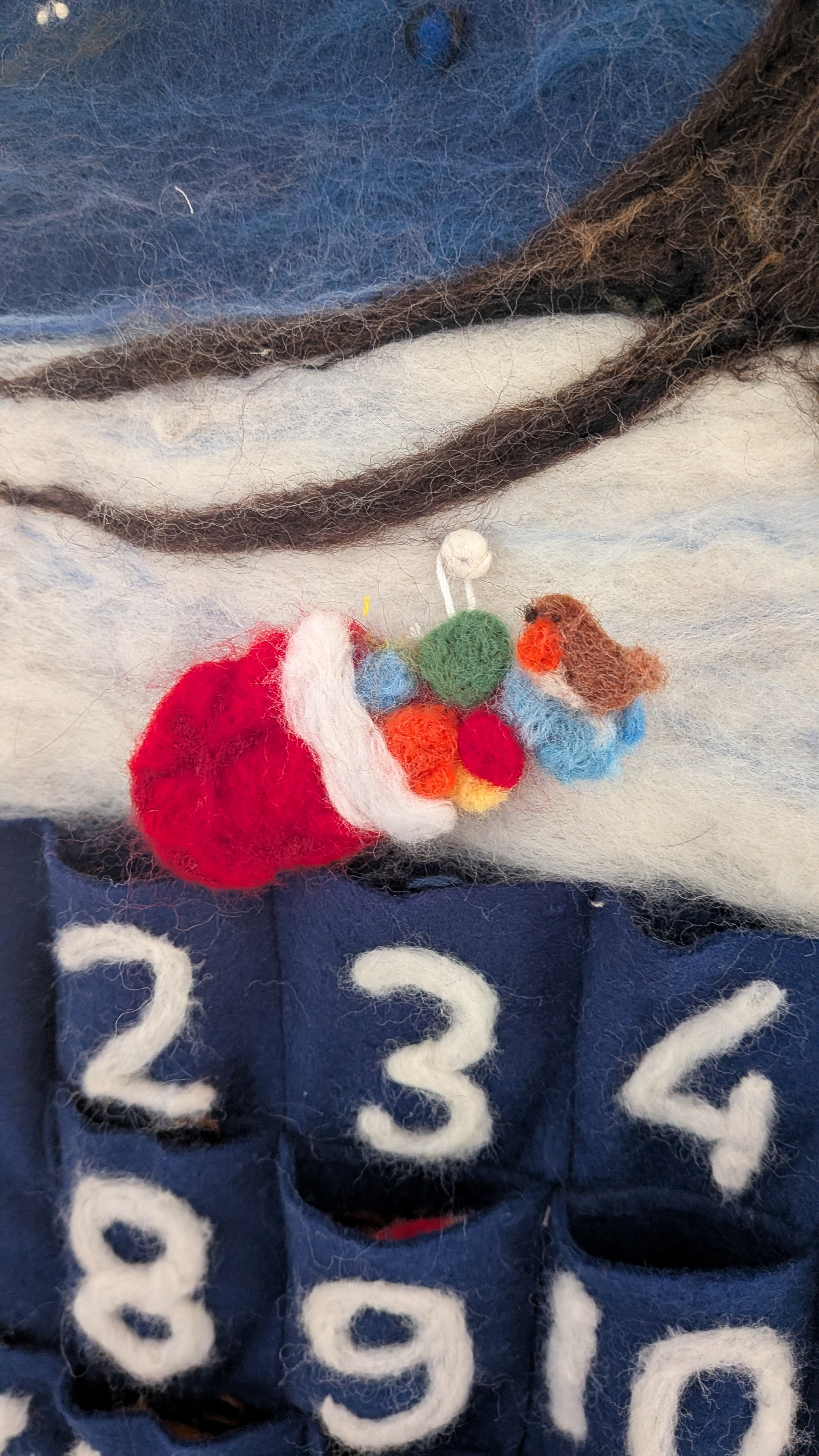a needle felted sack of baubles with a robin perched on top