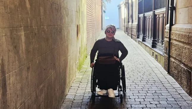 Melissa Parker in her wheelchair on a cobbled street with an overhanging roof