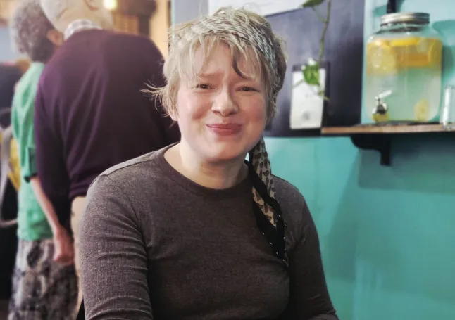 Melissa Parker (upper body only) in a cafe, looking straight into the camera