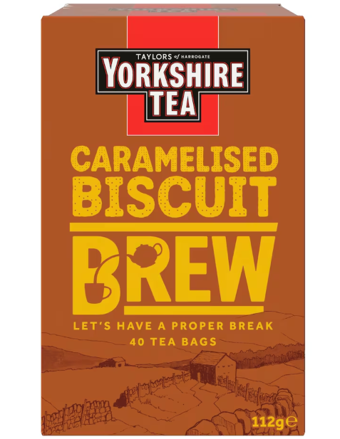 A box of Taylors of Harrogate Yorkshire Tea, Caramelised Biscuit Brew flavor. The packaging is primarily brown with a red vertical stripe at the top center behind the "Yorkshire Tea" logo. Below the logo, the words "CARAMELISED BISCUIT BREW" are printed in large yellow block letters. The word "BISCUIT" has a dotted texture, and the "B" in "BREW" contains a small illustration of a teapot pouring tea into a cup. The bottom of the box features a sepia-toned landscape illustration of a farm with a stone wall and barn, along with the text "LET'S HAVE A PROPER BREAK" and "40 TEA BAGS".