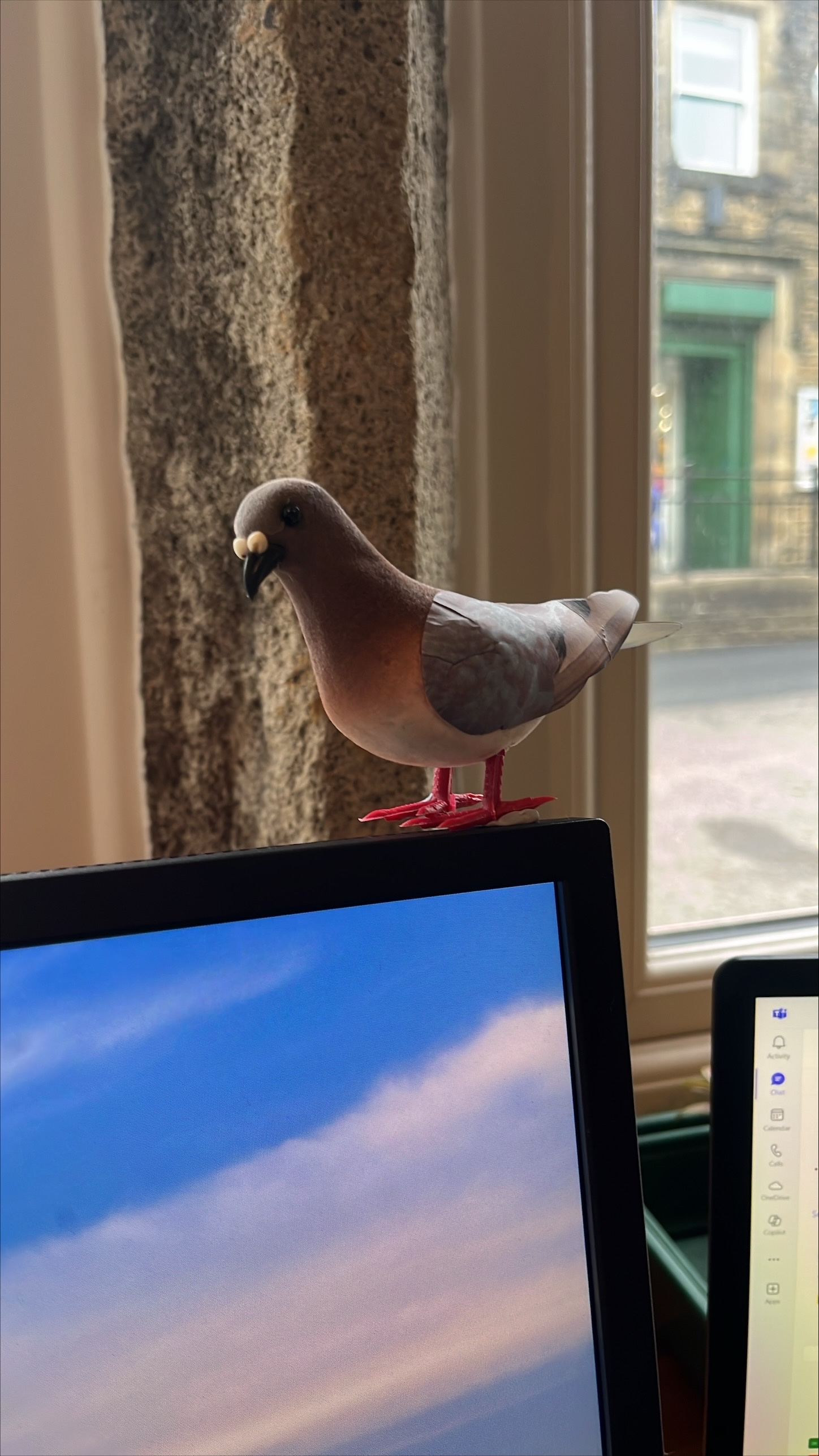 A small pigeon figure sat on top of a computer monitor