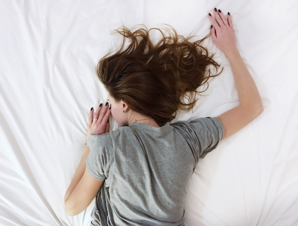 A woman face down on a bed with her hair spread over a pillow