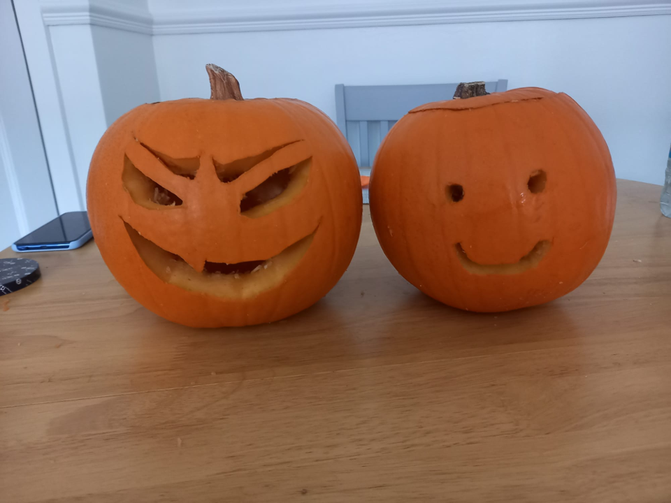 two pumpkins next to each other One is the traditional scary face and the other is a simple smiley face