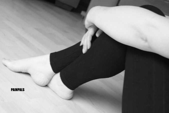 black and white image of crossed lower legs and bare feet with painpals watermark