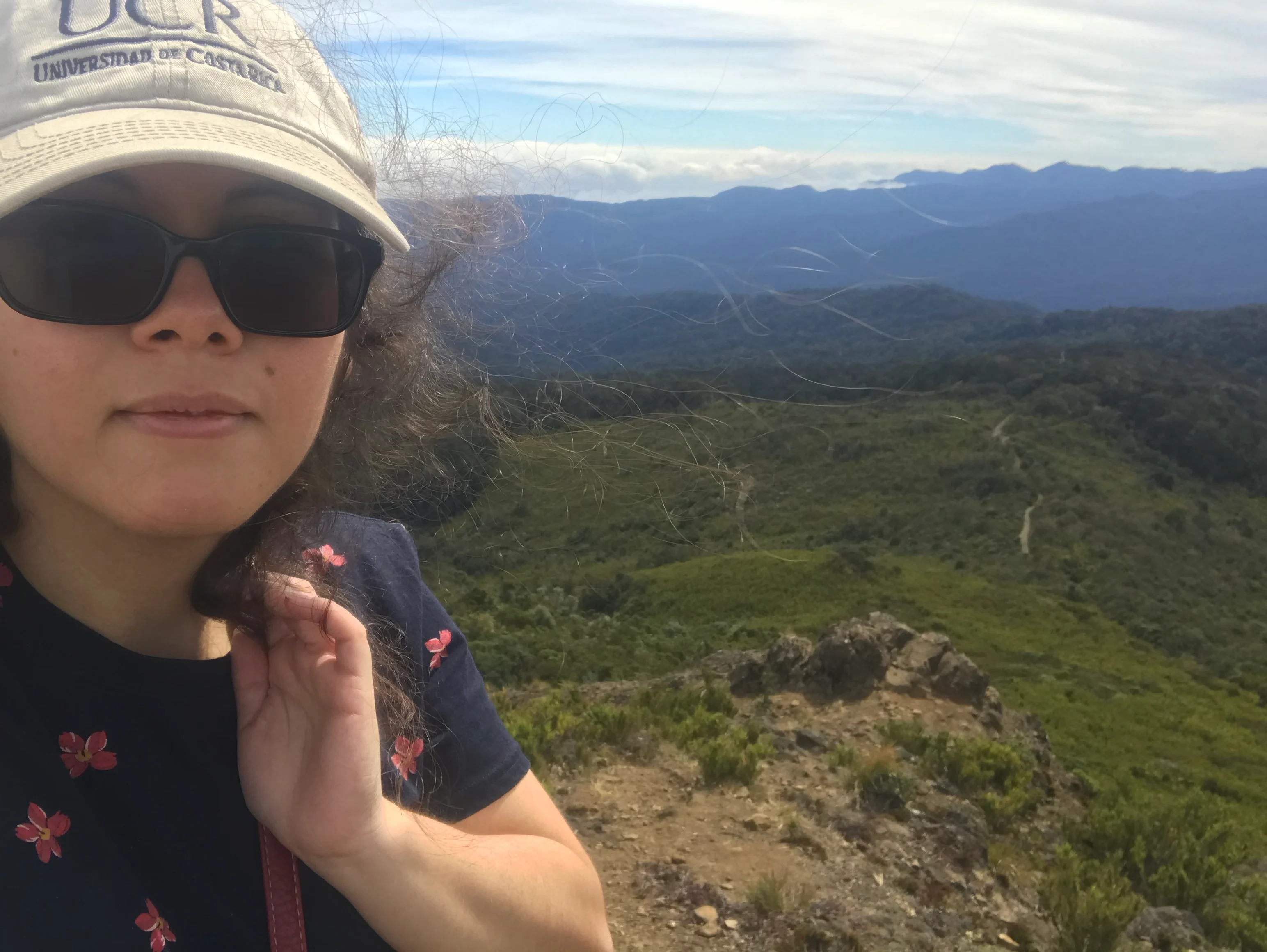 Rebeca stands on a hiking path with mountains in the distance